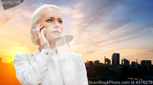 Image of serious businesswoman with smartphone outdoors