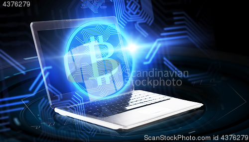 Image of laptop computer with bitcoin hologram