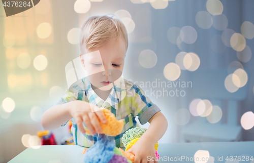 Image of happy little baby boy with ball clay at home