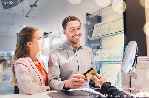 Image of happy couple choosing engagement ring in mall