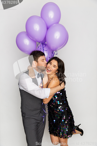 Image of happy couple with violet balloons kissing at party