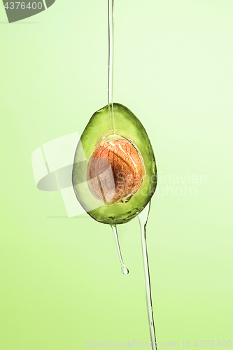 Image of Fresh avocado and oil on green background