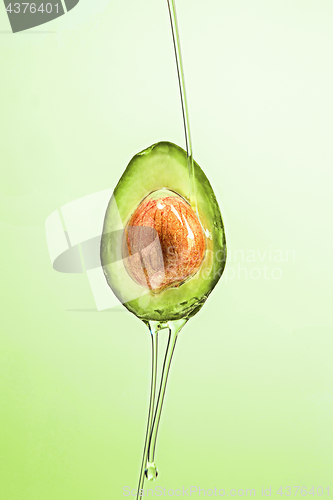 Image of Fresh avocado and oil on green background