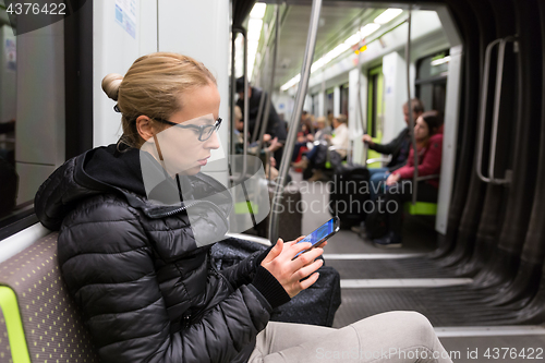 Image of Young girl reading from mobile phone screen in metro.