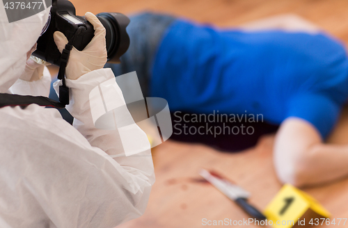 Image of criminalist photographing dead body at crime scene