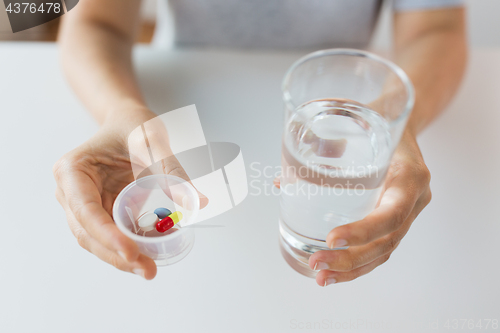 Image of close up of hands with pills and glass of water