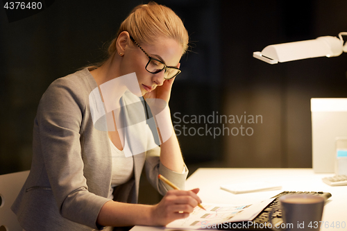 Image of businesswoman with papers working at night office