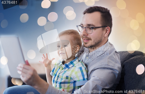 Image of father and son with tablet pc playing at home