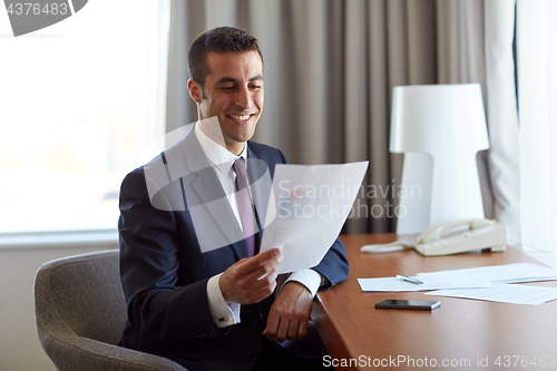 Image of businessman with papers working at hotel room