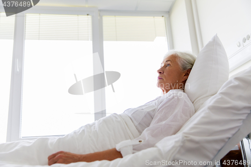 Image of sad senior woman lying on bed at hospital ward