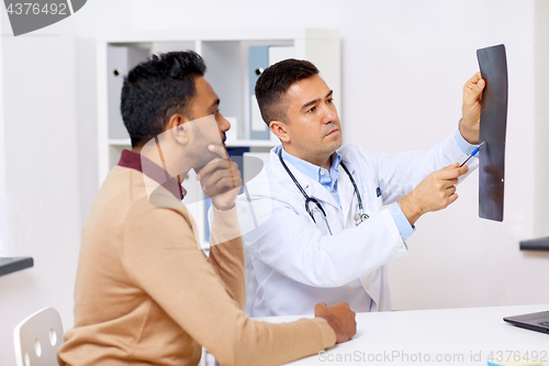 Image of doctor with x-ray and male patient at clinic