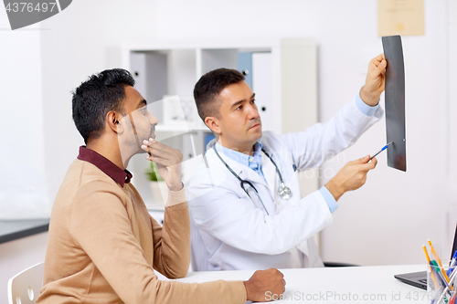 Image of doctor with x-ray and male patient at clinic