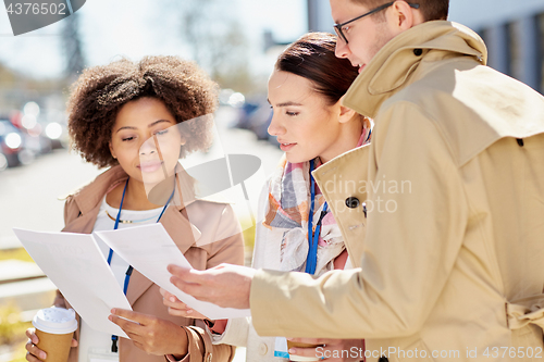 Image of international business team with papers outdoors