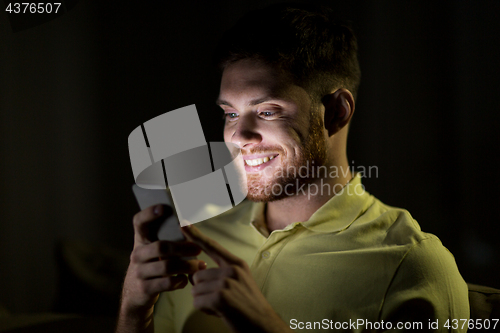 Image of happy young man with smartphone at night