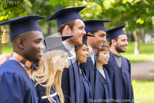 Image of happy students or bachelors in mortar boards