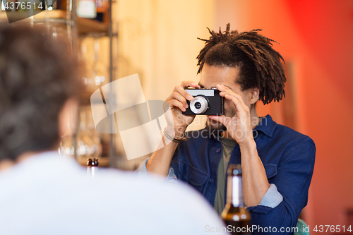 Image of man with camera photographing friend at bar