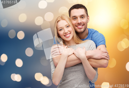 Image of happy couple hugging over lights background