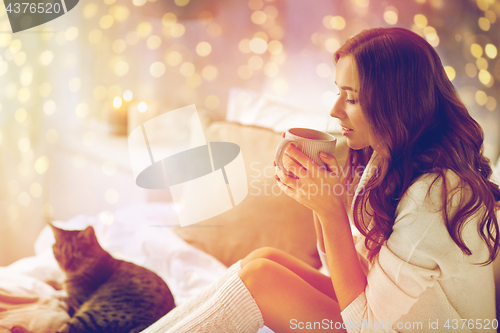 Image of happy woman with cup of coffee in bed at home