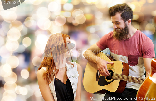 Image of couple of musicians playing guitar over lights