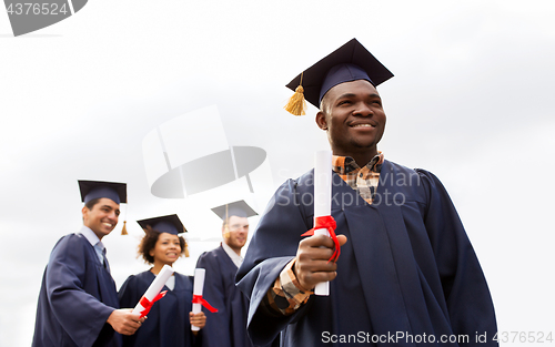 Image of happy students in mortar boards with diplomas