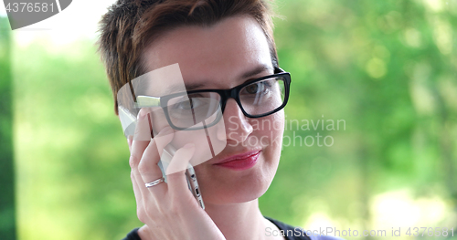 Image of Elegant Woman Using Mobile Phone by window in office building