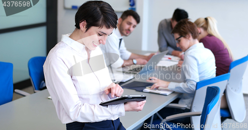 Image of Businesswoman using tablet with coworkers in backgorund having m