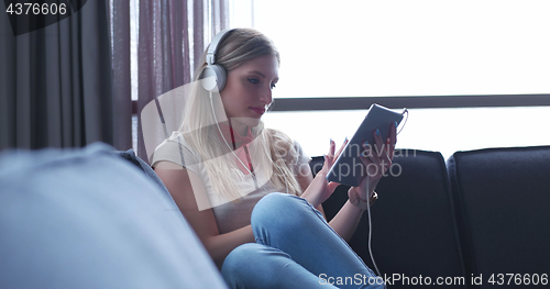 Image of Lovely Blond Woman Listening To Music while resting on couch