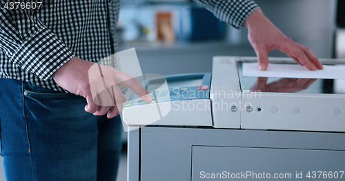 Image of Male Assistant Using Copy Machine in modern office