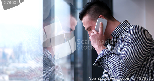 Image of Business Man Talking On Cell Phone, Looking Out Office Window