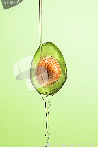 Image of Fresh avocado and oil on green background