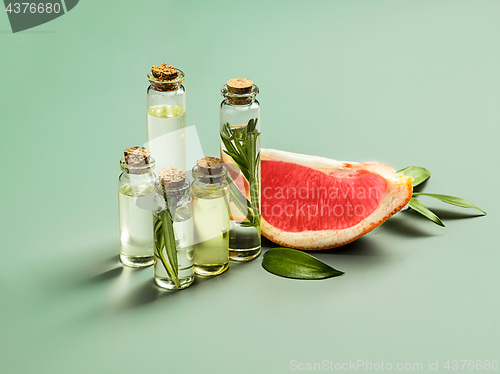 Image of Essential oil in glass bottle with fresh, juicy grapefruit and green leaves-beauty treatment.