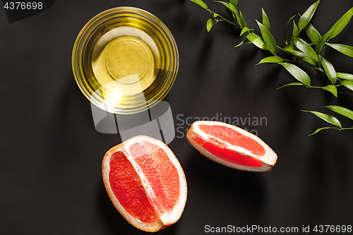 Image of Essential oil in glass bottle with fresh, juicy grapefruit and green leaves-beauty treatment.