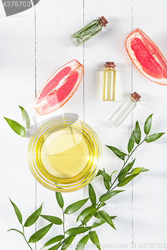 Image of Essential oil in glass bottle with fresh, juicy grapefruit and green leaves-beauty treatment.