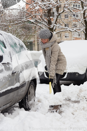 Image of Independent woman shoveling snow in winter.