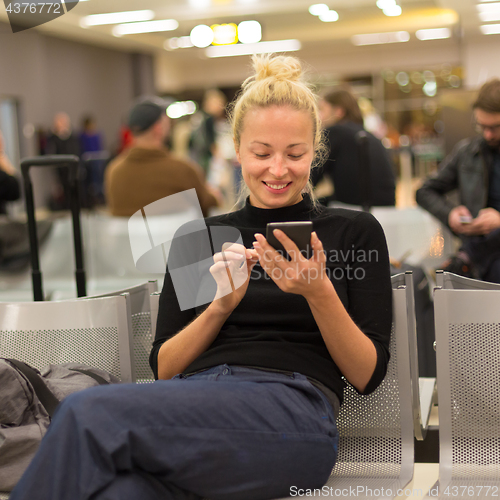 Image of Lady using smart phone while waiting at airpot departure gates.