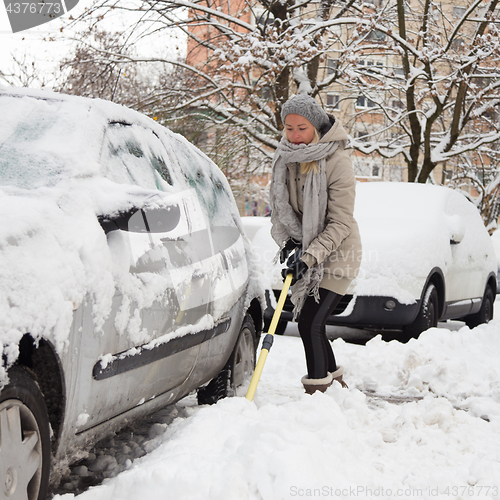 Image of Independent woman shoveling snow in winter.