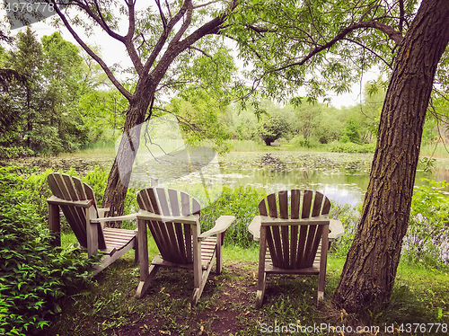 Image of Wooden chairs near a pond in the summer park