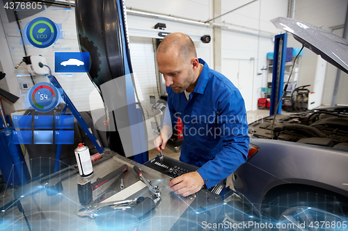 Image of mechanic man with wrench repairing car at workshop