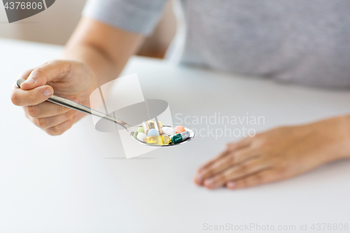 Image of close up of female hand holding spoon with pills