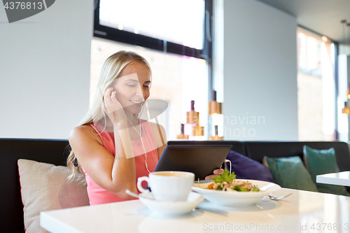 Image of happy young woman with tablet pc at restaurant