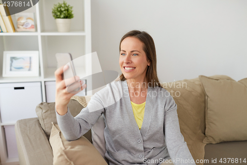 Image of happy woman taking selfie by smartphone at home