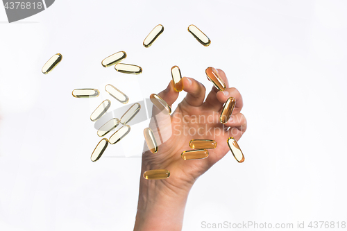 Image of hand picking cod liver oil capsules up