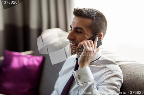 Image of businessman calling on smartphone at hotel room