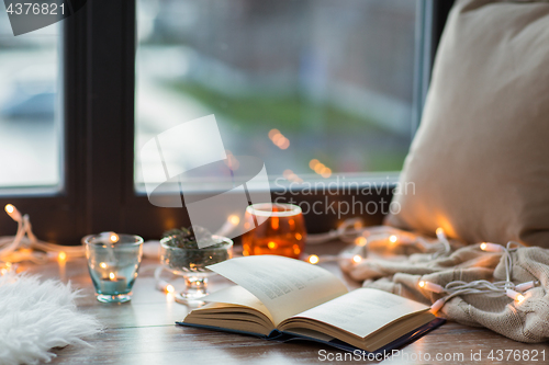 Image of book, garland lights and candles on window sill