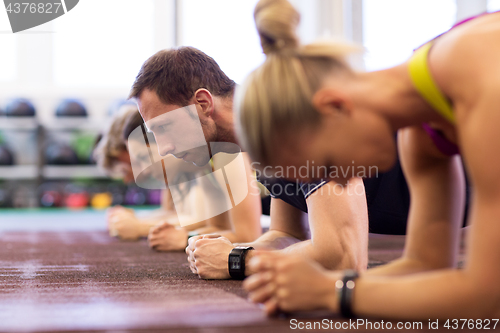 Image of man at group training doing plank exercise in gym