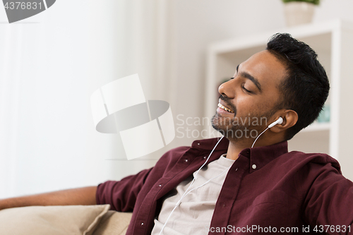 Image of happy man in earphones listening to music at home