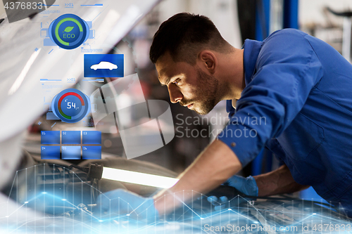 Image of mechanic man with lamp repairing car at workshop