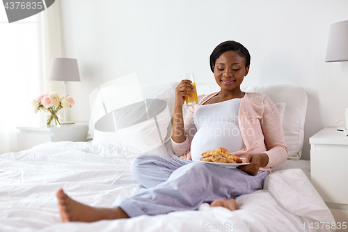 Image of happy pregnant woman with croissant buns at home