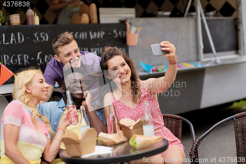 Image of happy young friends taking selfie at food truck
