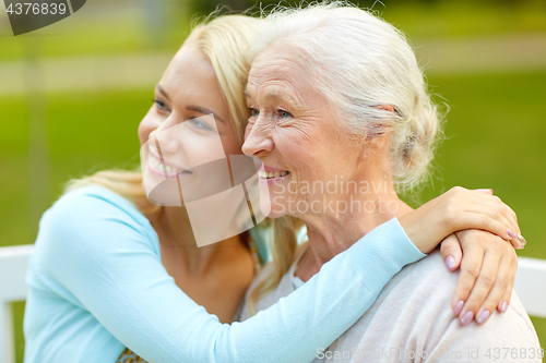 Image of daughter with senior mother hugging on park bench